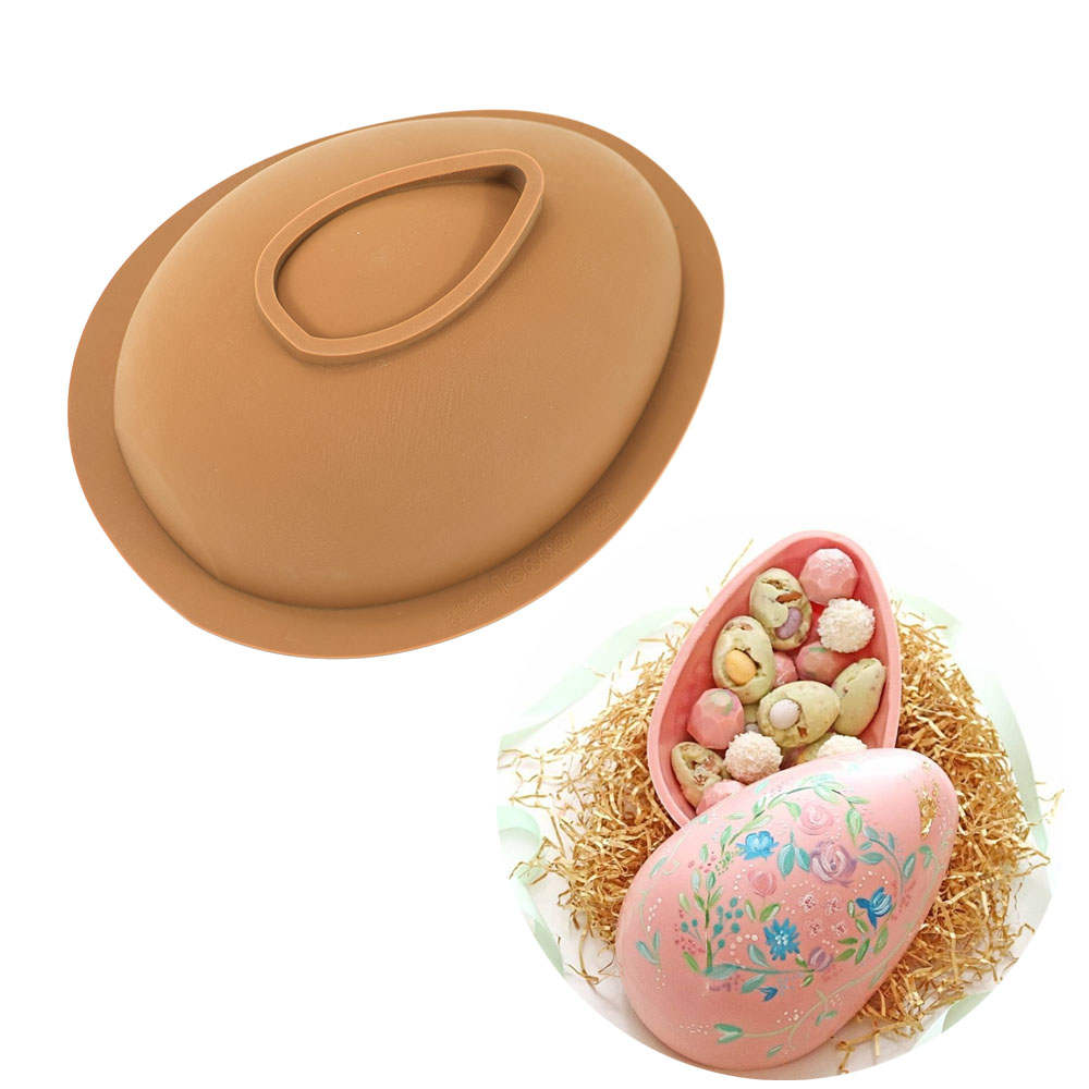 An image featuring a 3D egg silicone mold on top and a decorative egg filled with colorful candies below. The silicone mold is brown with an oval shape and a handle. The decorative egg is pink with floral designs and contains various small candies, sitting on a bed of straw.