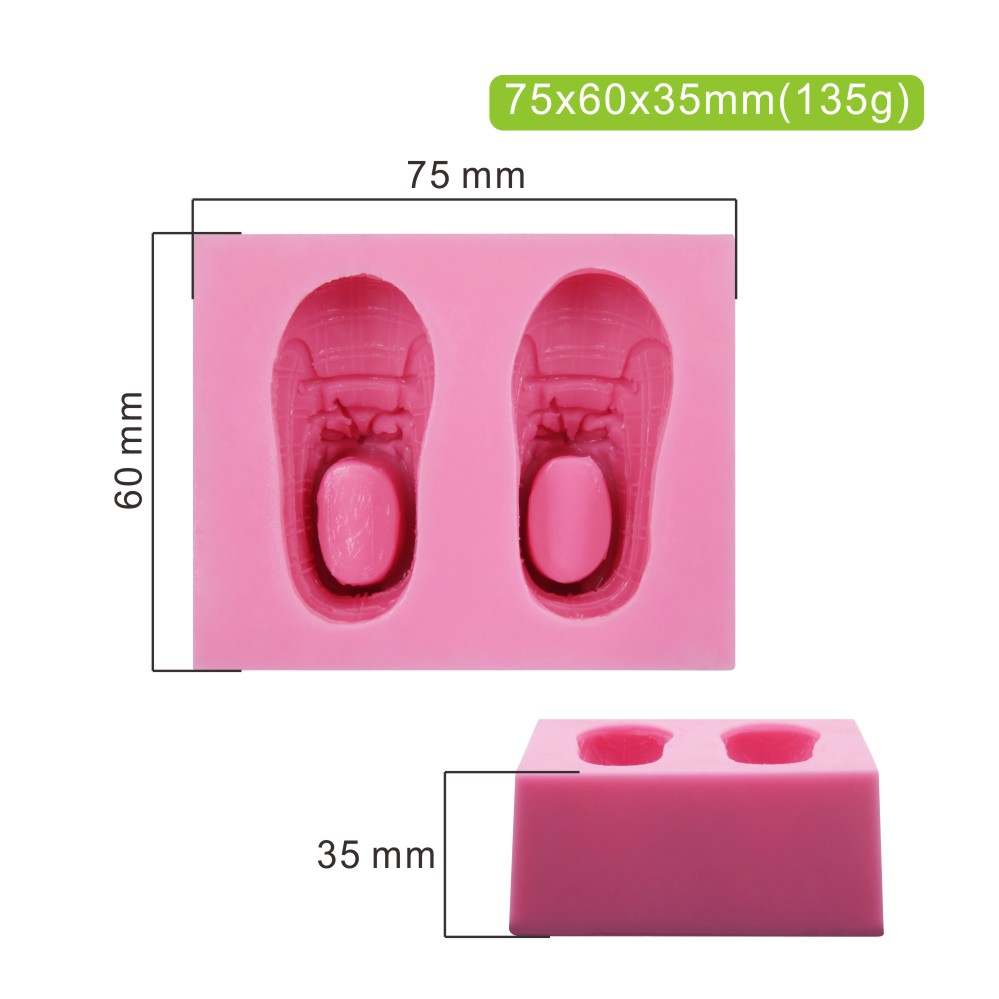 Image of a pink silicone mold designed to create baby shoe shapes. The mold features two detailed impressions of baby sneakers side by side, with dimensions of 75 mm x 60 mm x 35 mm. The design includes textured details such as laces and a tongue, and it is displayed alongside a scale indicating its measurements.
