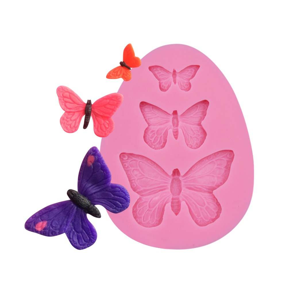 A pink silicone mold shaped like a butterfly with three butterfly impressions, accompanied by three colorful butterfly-shaped decorations in shades of pink, orange, and purple. The butterflies are positioned around the mold, showcasing the designs created from the mold.