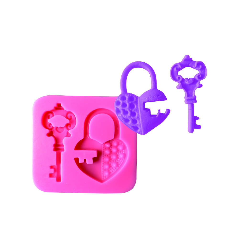 The image shows a pink silicone mould designed for creating heart lock and key shapes. The mould features a heart lock with a textured surface, along with two different key designs. One key is more ornate, while the other is simpler. All pieces are made from purple silicone and are displayed next to the mould.