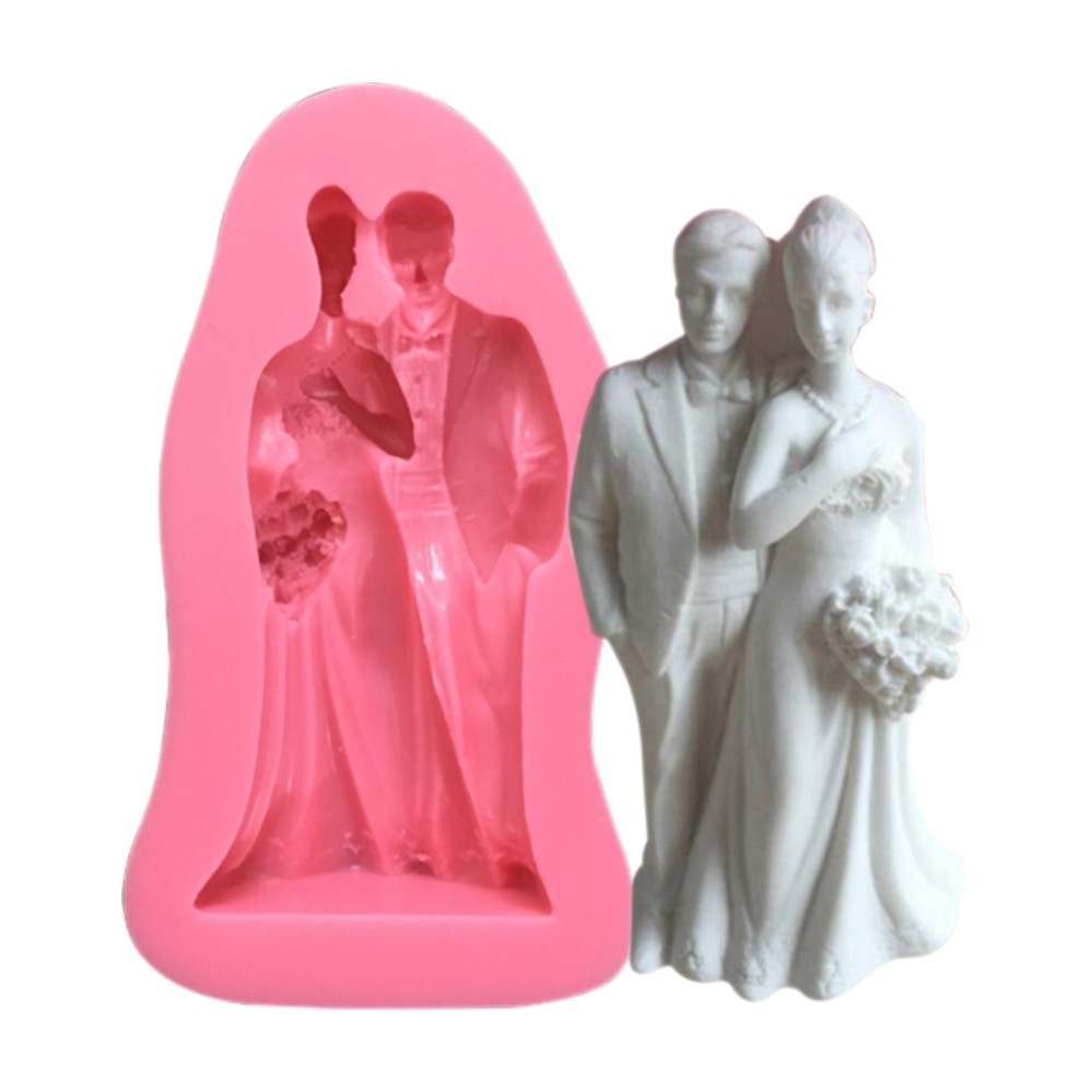 An image featuring a pink silicone mold designed to create a bride and groom figurine. The mold displays the outlines of a couple, with the bride wearing a long gown and holding a bouquet, and the groom in a tuxedo. Next to the mold is a white finished figurine of the same couple, showcasing their details and design. The overall theme is wedding-related, suitable for crafting or baking purposes.