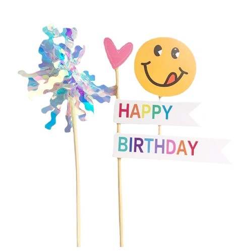 A three-piece birthday cake topper set featuring a colorful spiral design, a pink heart shape, and a cheerful yellow smiley face with a playful expression. The toppers include the words "HAPPY" and "BIRTHDAY" on white banners with multi-colored letters.