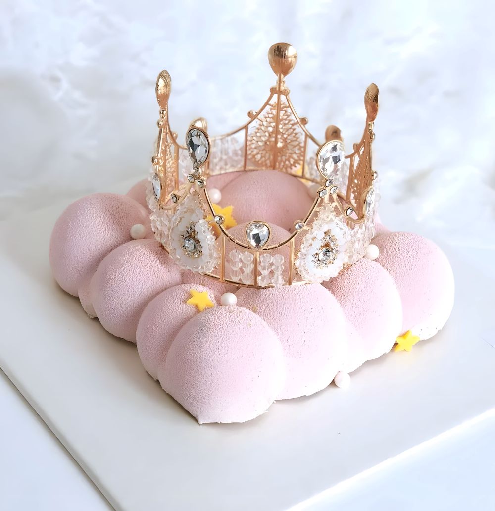 A festive cake adorned with a shiny crown on top, representing a special occasion.