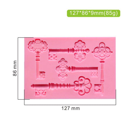 The image features a pink silicone mold designed for creating vintage antique key shapes. The mold includes several intricate key designs, each with decorative elements. Dimensions on the image indicate the mold is 127 mm by 86 mm, with a thickness of 9 mm, and it weighs 85 grams. The keys vary in style and detail, making it suitable for crafting decorative items.
