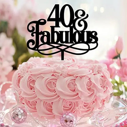 A round cake decorated with pink rose-shaped frosting sits on a table. Atop the cake is a black cake topper that reads "40 &amp; Fabulous" in an elegant font. The background features soft pinks and pastel colors, with decorative elements adding to a celebratory atmosphere.