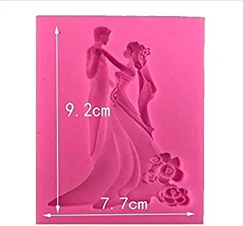 A pink silicone mould featuring a relief design of a bride and groom dancing. The mould measures approximately 9.2 cm in height and 7.7 cm in width. The bride is depicted wearing a long gown, and there are decorative flowers at the bottom of the design.