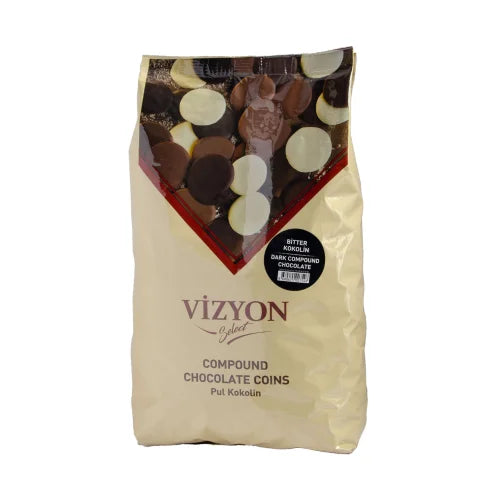 A cream-colored bag of Vizyon brand compound chocolate coins weighing 2.5 kg. The bag features a red triangular design at the top, showcasing various chocolate coins in dark and white colors. A black sticker indicates the product is &quot;Bitter Kivilcim&quot; dark compound chocolate. The product name &quot;Vizyon&quot; is prominently displayed in a stylish font on the front.