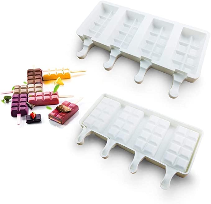 The image features two white silicone molds designed for making square-shaped cake popsicles, each mold containing four cavities. In the background, several colorful cakesicles are displayed, showcasing various flavors and toppings, with wooden sticks for easy handling. The molds have handles for easy removal of the treats once frozen.
