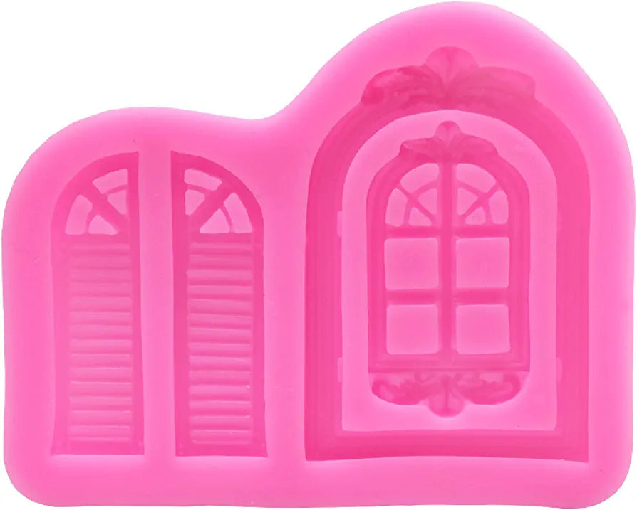 A pink silicone mould designed to create castle-themed windows and doors. The mould features two window designs: one with shutters and one larger, decorative window with a rounded top and intricate detailing, including a floral motif at the top. The mould is flexible and allows for easy release of the finished shapes.