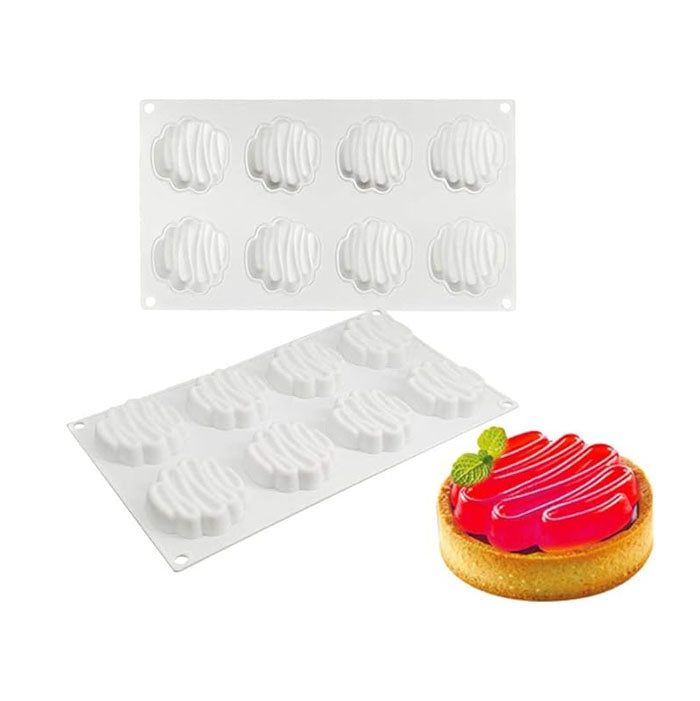 A silicone mould for baking, featuring a zigzag design with eight cavities, displayed above a finished dessert. The dessert is a round pastry with a golden crust, topped with red jelly and garnished with mint leaves, showcasing the mould&