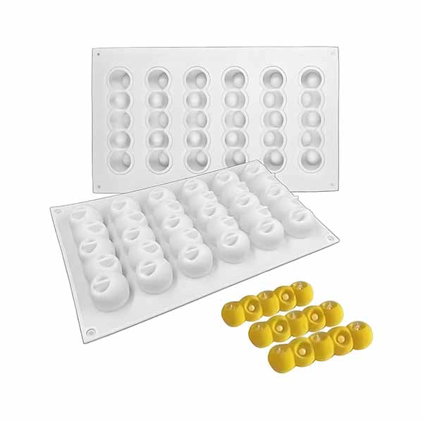 A set of white silicone molds featuring six rows of concave ball shapes, shown in various configurations. The image also includes examples of yellow treats created using the mold, illustrating its use for desserts or pastries.