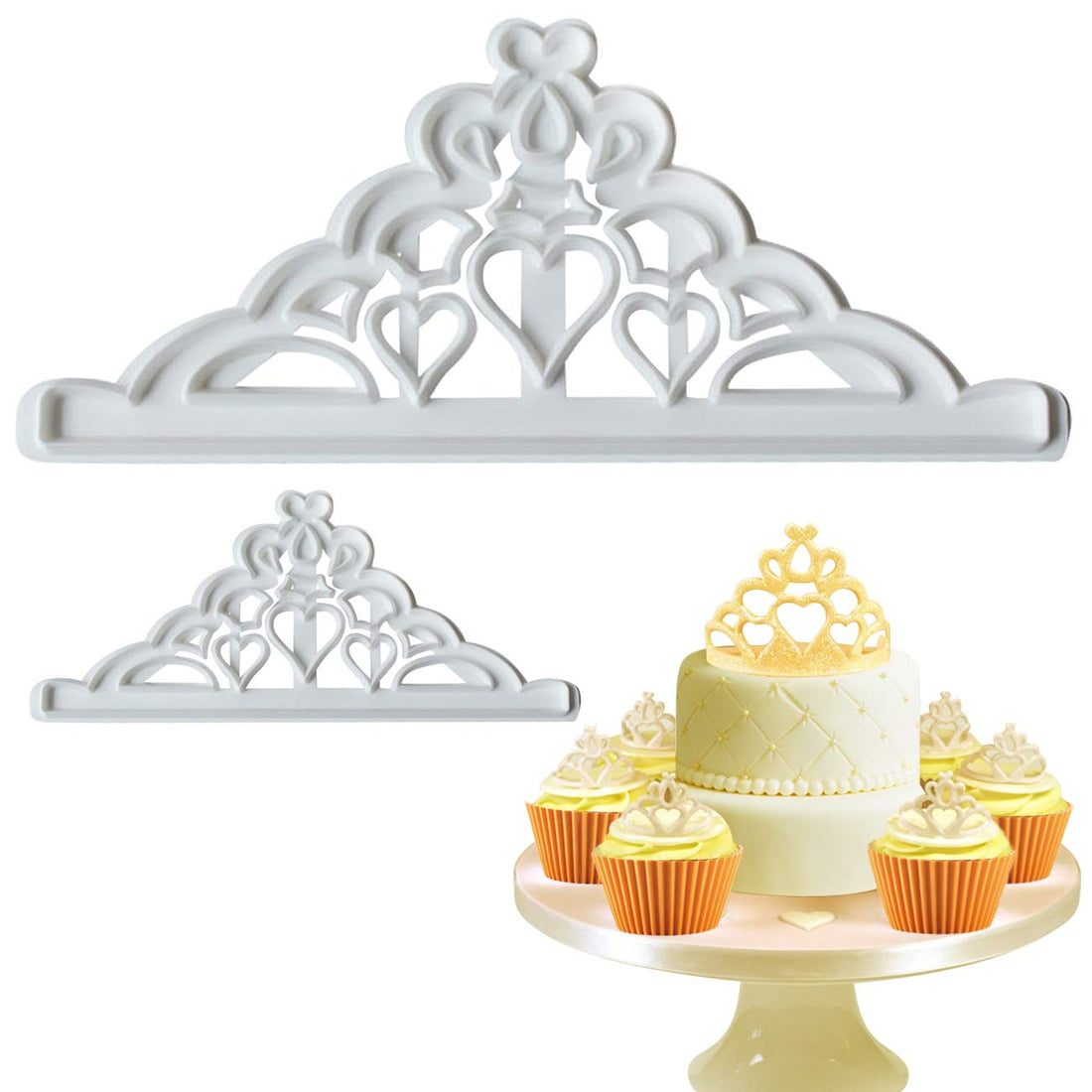 An image showing a set of two white crown-shaped cookie cutters. The larger cutter is at the top, featuring intricate designs with bows and hearts, while a smaller version sits below it. In the foreground, a decorated cake adorned with a gold crown topper is displayed on a cake stand, surrounded by orange cupcakes with cream frosting and similar crown decorations on top.