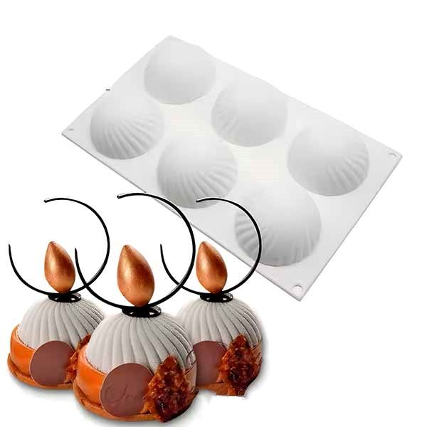 A white silicone cake mold with six spiral round cavities is shown at the top of the image. Below the mold, there are three decorative pastries featuring a rounded shape with white frosting, a chocolate disc, and an orange glaze, each topped with a golden almond-shaped decoration and a curved black wire handle.