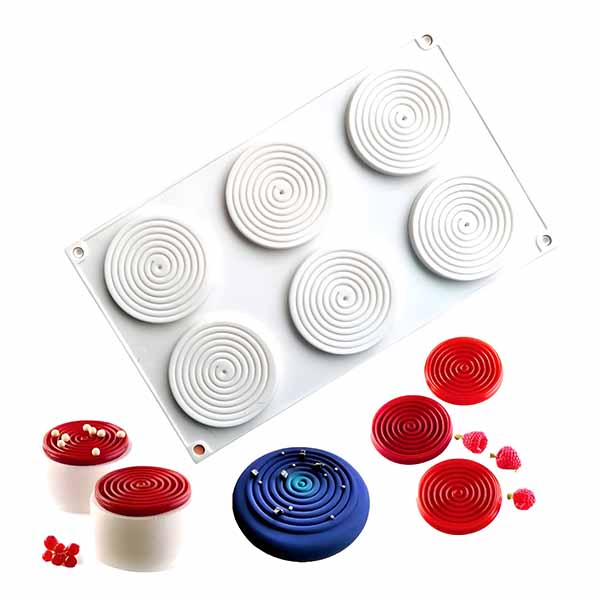 A 6 cavity silicone mold shaped like spirals in white, positioned at the top. Below, there are several completed spiral-shaped desserts in various colors: red, blue, and white, along with some small red decorative items resembling berries.