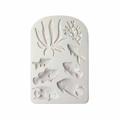 An image of a white silicone mold featuring various sea-themed designs. The mold is shaped like a rectangle with rounded edges and includes detailed impressions of several fish and aquatic plants, including two types of fish, as well as leafy seaweed and coral designs at the top. The overall texture of the mold looks smooth, suitable for creating decorative items or baked goods in these shapes.