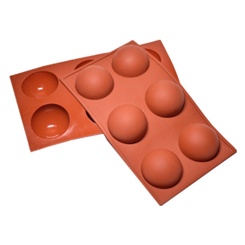 Two silicone chocolate molds featuring six half-sphere cavities in total. The molds are a reddish-brown color, with three cavities prominently visible on the top mold and three on the bottom mold. The molds are presented in a flat position, showcasing their rounded shapes.