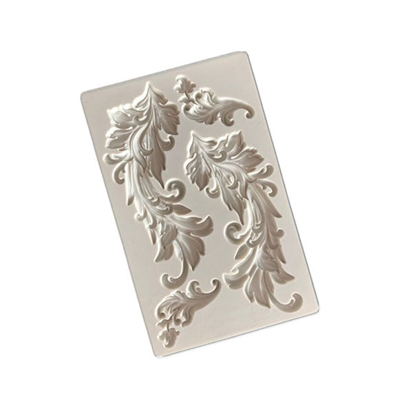 The image features a baroque swirls silicone mould, designed for crafting intricate designs. The mould is rectangular and light-colored, showcasing two ornate, swirling patterns that resemble leaves or flourishes. The designs are detailed, with curves and waves, providing decorative elements suitable for various creative projects.