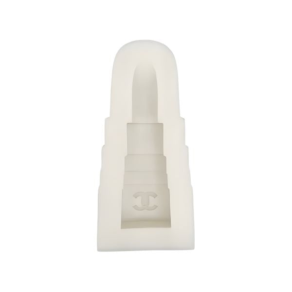 A silicone mold shaped like a lipstick container. The mold is semi-transparent and features distinct sections resembling the base and tip of a lipstick tube. An emblem is visible on the front of the mold, indicating a brand design. The entire mold is in a cream or light-colored silicone material.