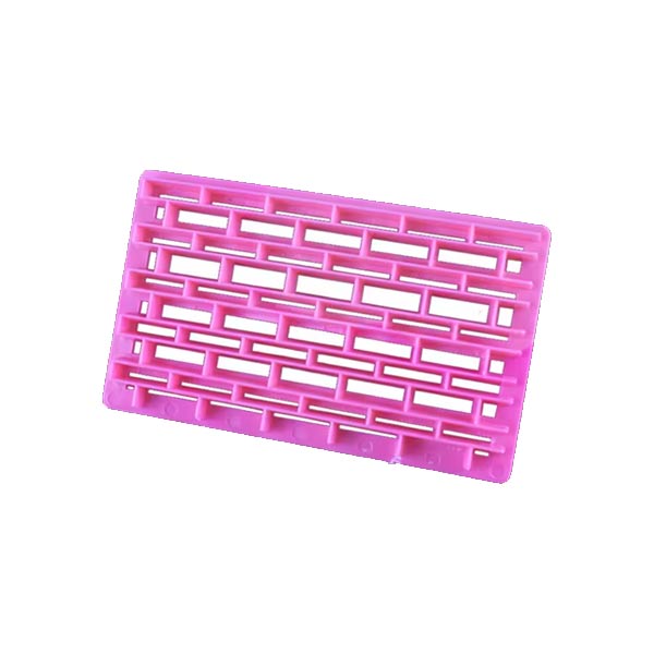 Pink plastic cutter shaped like a brick pattern with rectangular openings, designed for embossing or cutting quilt fabric. The cutter has a flat surface and is shown at a slight angle.