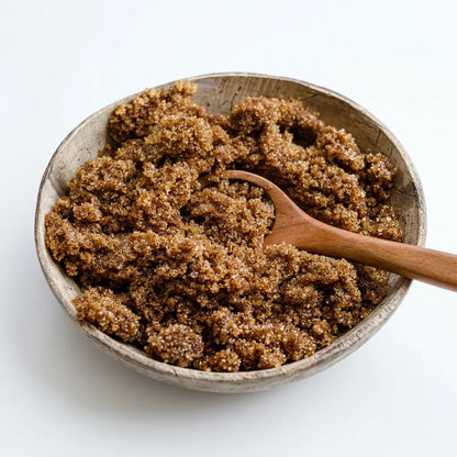 Brown sugar in a rustic wooden bowl with a wooden spoon, photographed on a clean white background.