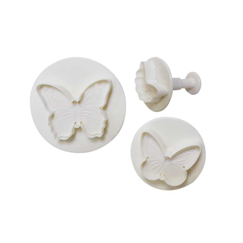 Three white plunger cutters designed in the shape of butterflies are displayed. The set includes two round cutters featuring detailed butterfly designs and one smaller cutter with a similar butterfly motif. The designs show delicate wing patterns making them suitable for creating decorative shapes in various foods or crafts.