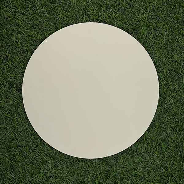 A round, thick cake drum in warm white color, measuring 10mm in thickness, is displayed on a green grass-like surface. The drum has a smooth, flat surface and a circular shape.