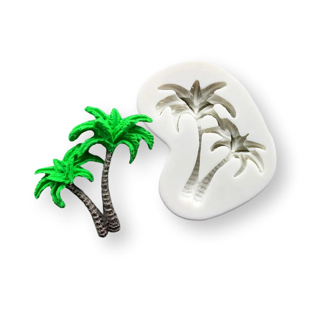 A palm tree silicone mold displayed alongside a small, brightly colored green palm tree figurine. The mold is white and features an impression of two palm trees, while the figurine shows vibrant green leaves and textured brown trunks.