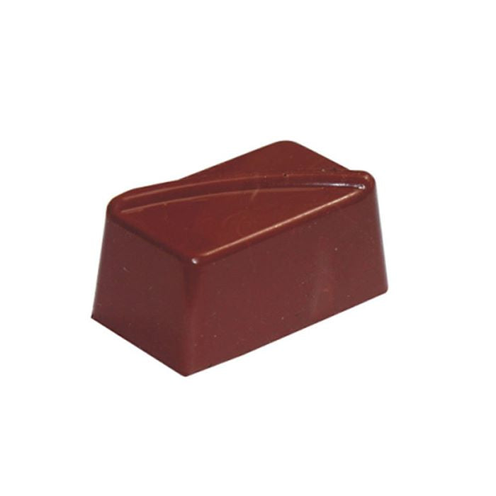 The image shows a single piece of chocolate shaped like a rectangular prism with a diagonal top surface. The chocolate has a smooth, shiny brown surface, and its edges are slightly rounded. There are subtle lines on the top that create a decorative design.