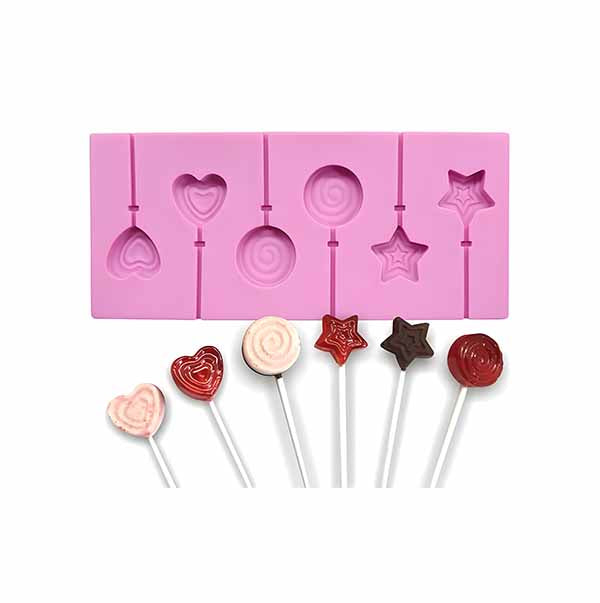 A pink silicone lollipop mold featuring five cavities in various shapes: two hearts, a swirl, and two stars. Below the mold, there are four completed lollipops on sticks in different colors and designs: a red heart, a light pink swirl, a dark star, and a red round lollipop.