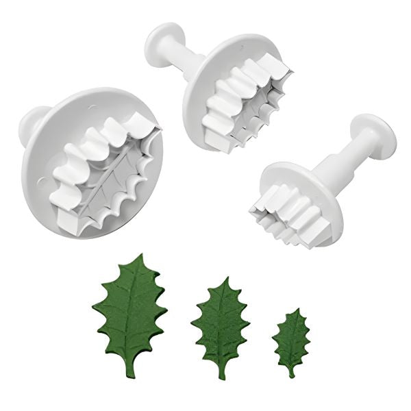 A leaf plunger set consisting of three white plastic plunger cutters in different sizes. The cutters have textured edges for detailing and are used to create leaf shapes. Three green leaf-shaped cutouts are displayed in front, showcasing the finished leaf designs.