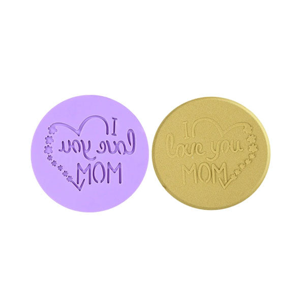 The image features two circular cookie stamps designed for embossing fondant. On the left, a lavender-colored stamp has the text &quot;I love you MOM&quot; inside a heart, with decorative flowers. On the right, a gold-colored stamp displays a similar message with the phrase &quot;I love you MOM&quot; also enclosed in a heart shape. Both stamps are shown side by side against a white background.