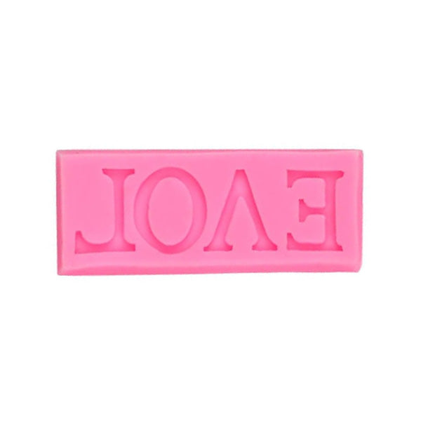 A pink silicone mould in the shape of the word "LOVE," displayed upside down. The letters are embossed, allowing for creating raised designs. The mould is rectangular and smooth, suitable for use in baking or crafts.