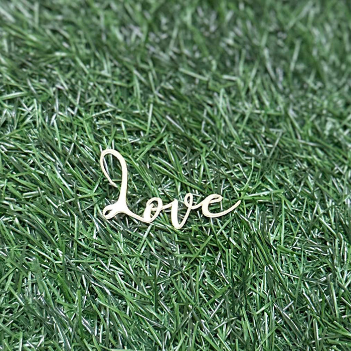 A customized cake topper featuring the word &quot;love&quot; in an elegant, cursive font. The topper is displayed on a background of green artificial grass. The design is simple and decorative, suitable for cake decoration.