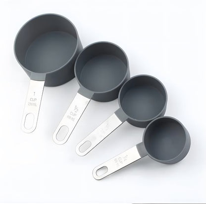 A set of four measuring cups displayed in a row. The cups are gray with stainless steel handles. The measurements labeled on the handles include 1 cup (25 ml), 1/2 cup (118 ml), 1/3 cup (80 ml), and 1/4 cup (60 ml).