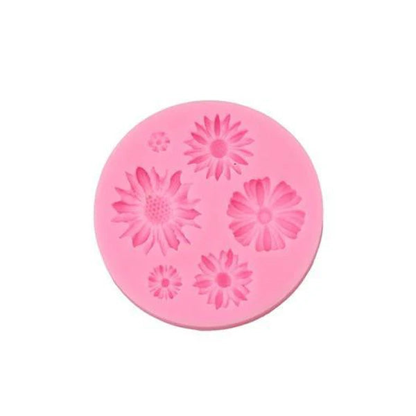 A circular, pink silicone mold designed for creating mini flower shapes. The mold features various floral designs, including different sizes and types of flowers, each with intricate details. The flowers are raised in relief, showing textures typical of petals and centers, making it suitable for baking or crafting purposes.