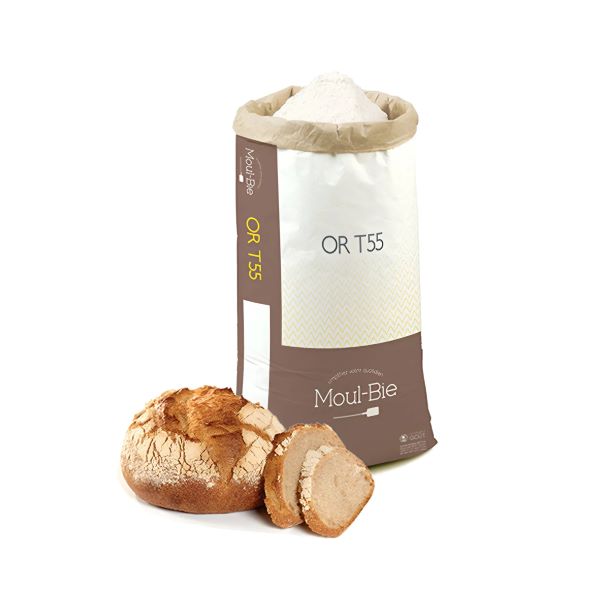 A bag of flour labeled &quot;Moul-Bie OR T55&quot; stands upright, with a light tan color and a white top. Next to the bag is a round loaf of bread with a crusty exterior, and a slice of the bread is shown on the side, revealing its soft, light-colored interior.