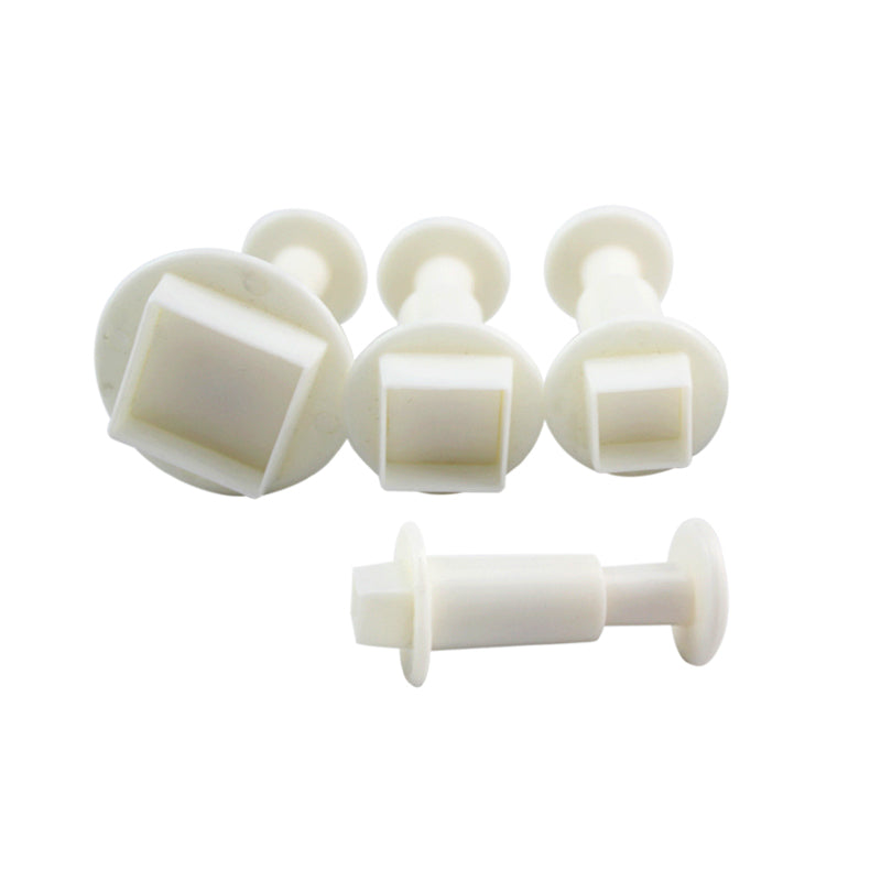 A set of four square-shaped plunger cutters in white plastic. The cutters have a round handle and a square cutting edge, designed for baking or crafting purposes. They are arranged with three cutters upright and one lying horizontally in the foreground.