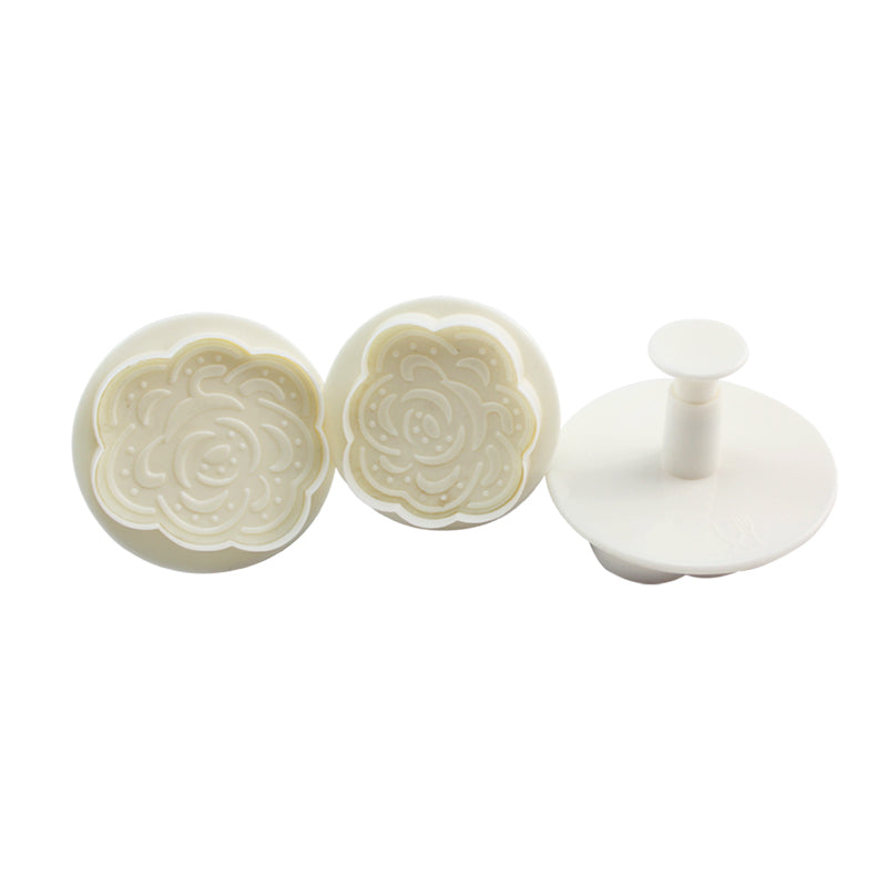 A set of three rose-shaped plunger cutters in light cream color. Two circular cutters feature intricate rose designs, while the third is a plunger tool for easily pressing out the shapes. The cutters are arranged horizontally, showing their detailed floral patterns.