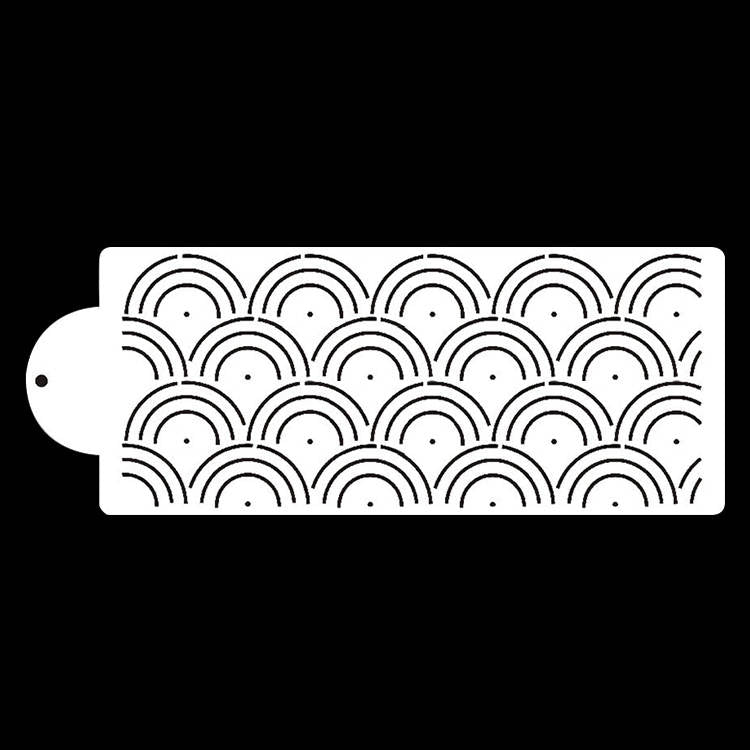 A white cake stencil featuring a repeating pattern of half-circle arches, resembling waves or scallops. The stencil has a rounded end with a hole for easy handling. The design includes small dots within the arches, creating an intricate texture. The background is black, emphasizing the white stencil design.