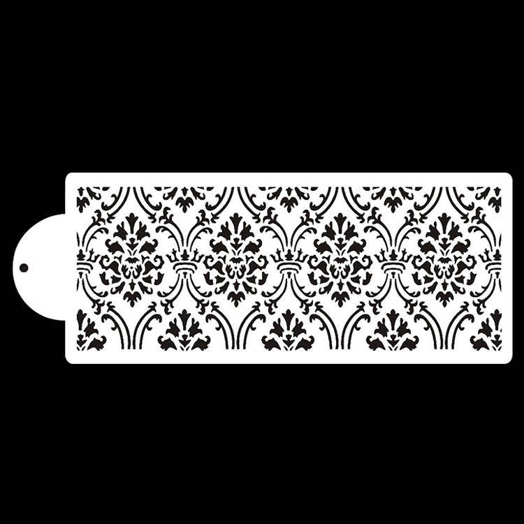 A white cake stencil featuring a repeating damask pattern in black. The stencil has a rounded end with a hole for easy grip and placement. The design consists of floral and scroll motifs arranged symmetrically across the surface.