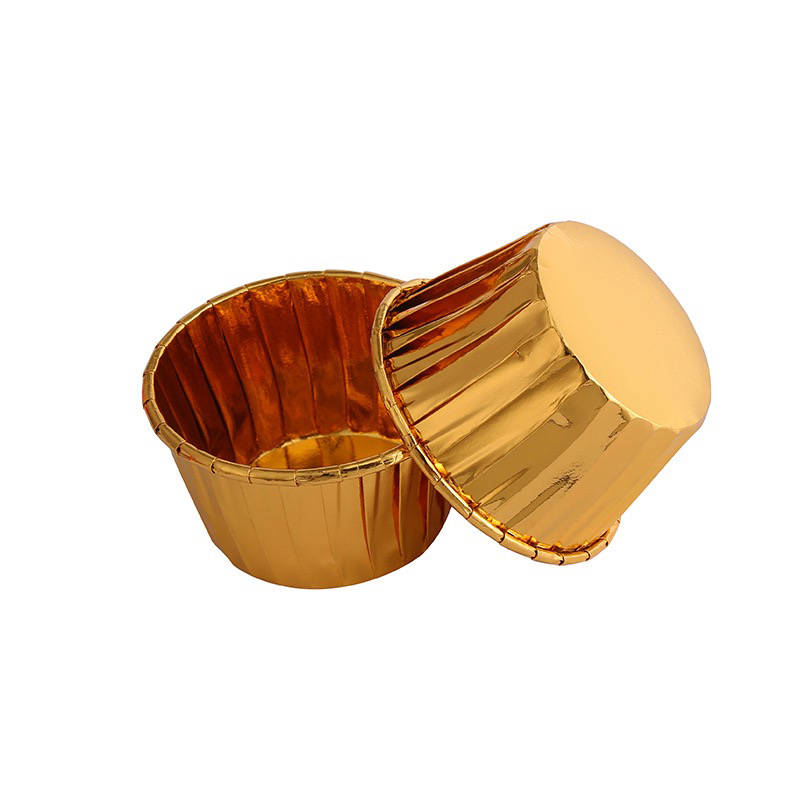 Two shiny golden aluminum ramekins are pictured, one upright and the other turned upside down beside it. The ramekins have a fluted texture on their sides and appear to be made of reflective material. This image represents a product offering of 50 aluminum foil baking cups.