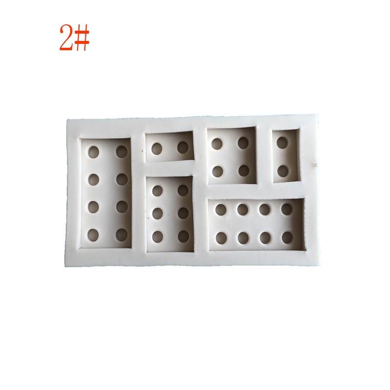 A white silicone mold designed to create LEGO brick shapes. The mold features several rectangular sections, each with various configurations of circular indentations resembling LEGO stud patterns. The background is plain, highlighting the mold&