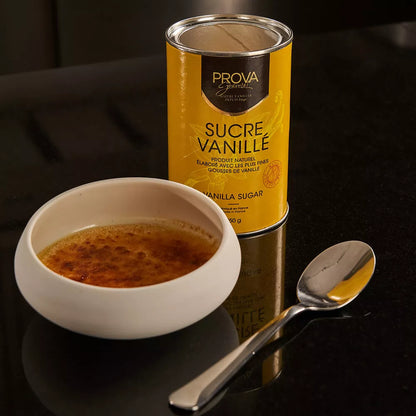 Can of Prova Vanilla Sugar next to a bowl of vanilla sugar on a dark surface