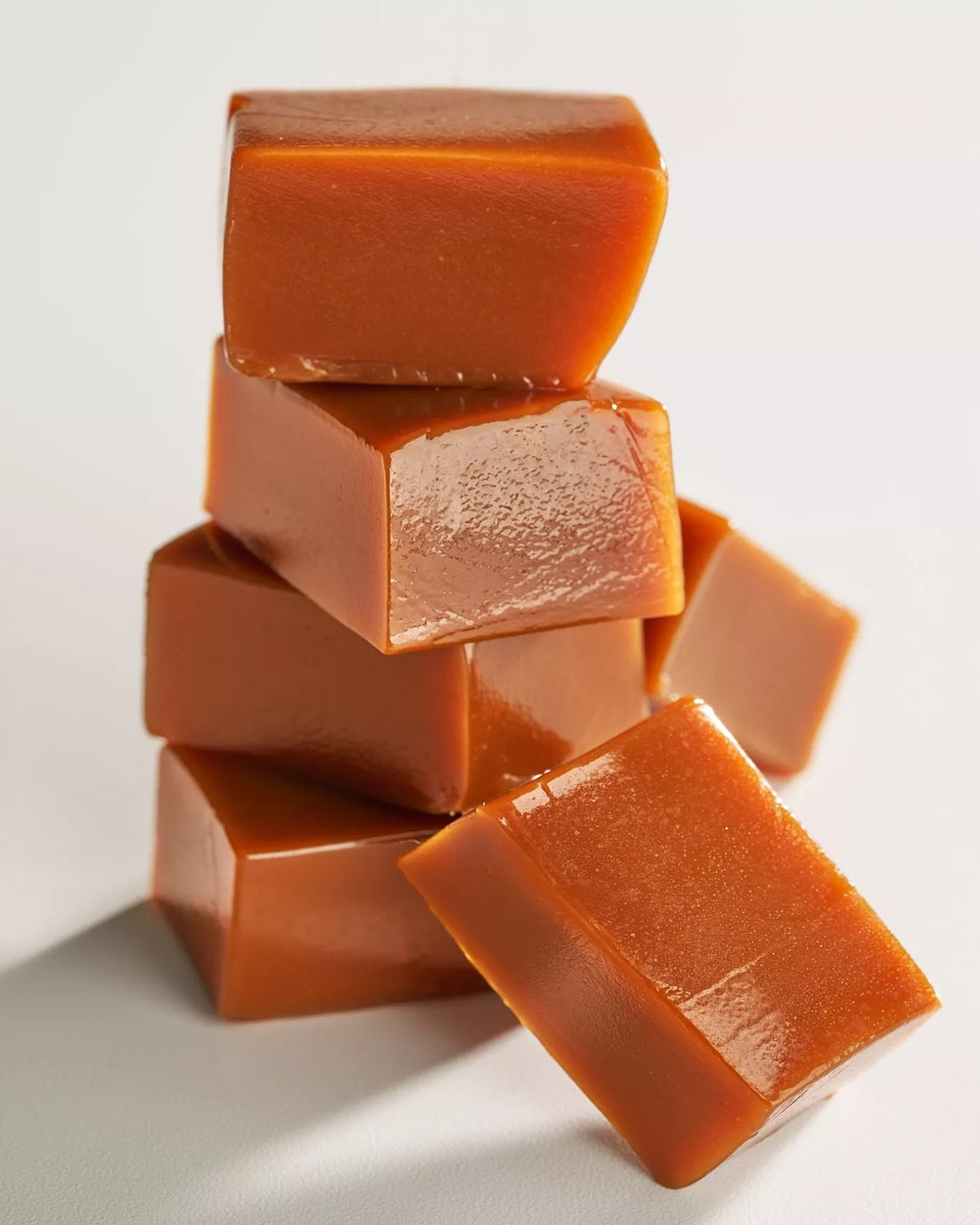 Stack of caramel squares on a white background