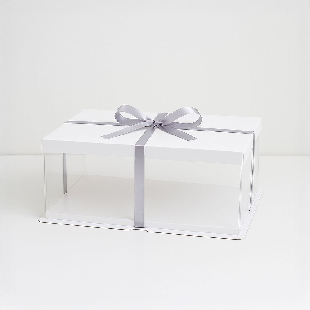 A white box topped with a silver ribbon, suggesting a festive gift awaiting presentation or unwrapping.