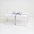 A white box topped with a silver ribbon, suggesting a festive gift awaiting presentation or unwrapping.