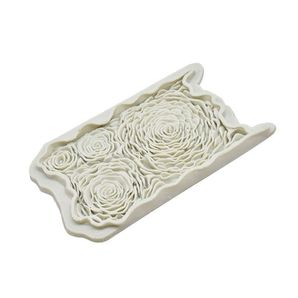 A white silicone mould designed in the shape of three rose flowers. The mould features intricate detailing that replicates the layered petals of the roses, presented in a rectangular format.