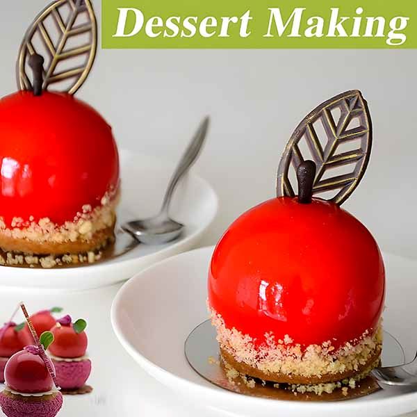 An elegant presentation of two dessert spheres that resemble shiny red apples, each topped with a chocolate leaf and sitting on a base of crumbled biscuit. The desserts are served in white plates, accompanied by a silver spoon. The upper part of the image features the text "Dessert Making." In the bottom corner, there are smaller images of other colorful desserts like macarons and smaller spheres, enhancing the theme of dessert creation.