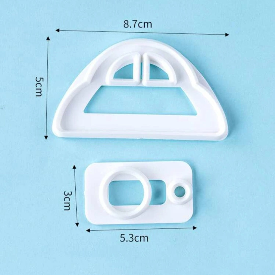 The image features two pieces of white plastic cookie cutters set against a light blue background. The larger cutter, shaped like the front of a car, measures 8.7 cm in width and 5 cm in height. It has windows and a smooth outline. The smaller cutter, resembling a car door, measures 5.3 cm in width and 3 cm in height. Both pieces are neatly arranged, with their dimensions indicated by arrows. The overall design is simple and suitable for making car-shaped cookies.