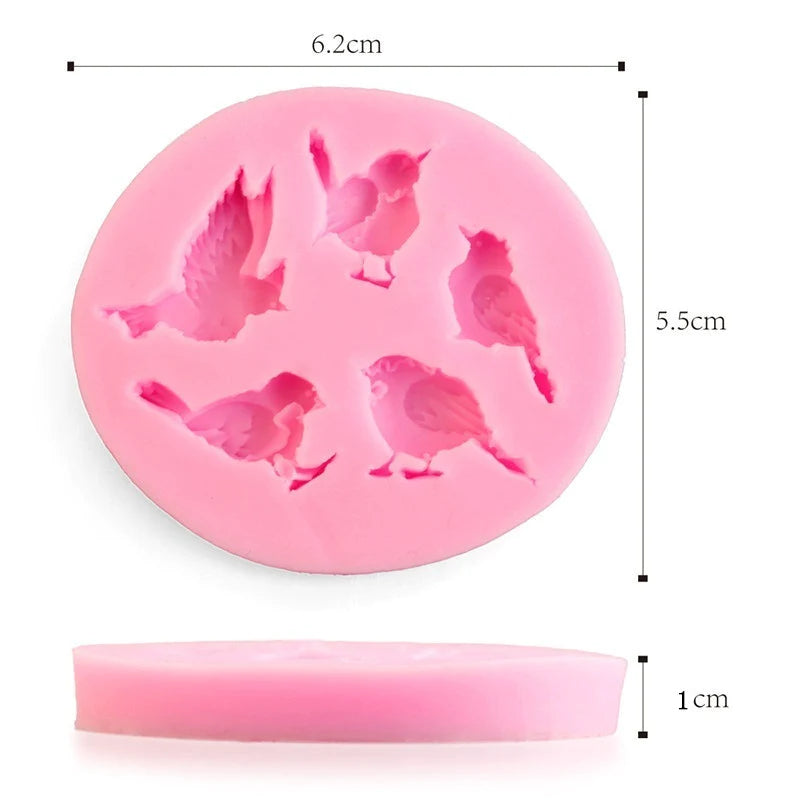 An image of a pink silicone mould shaped like various birds. The mould is round with five bird designs visible on the surface, depicting different poses. The dimensions of the mould are approximately 6.2 cm in diameter, 5.5 cm in height, and 1 cm in thickness. The mould is shown from the side and above, highlighting its detailed bird designs and overall shape.